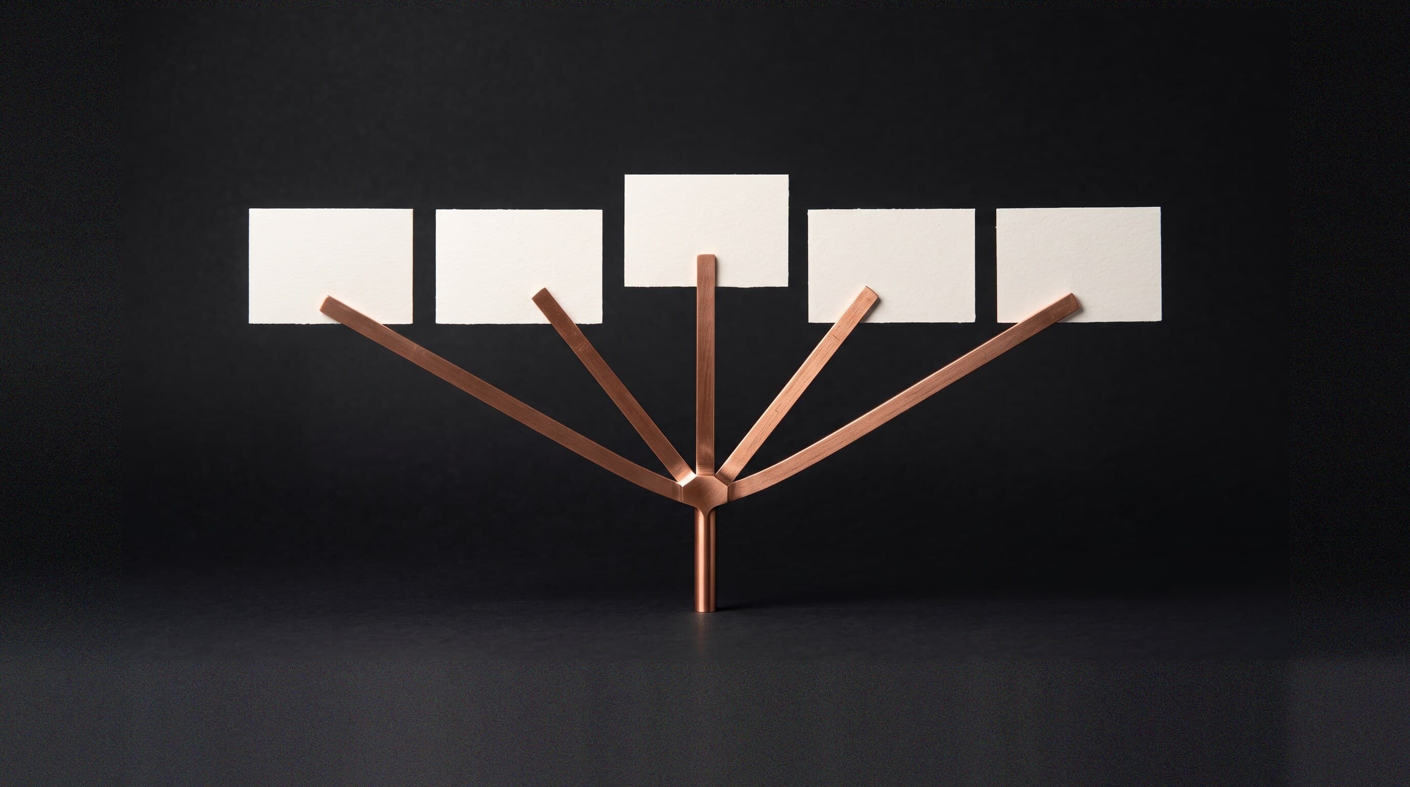 A machined copper stem branching at a single junction into five arms, each holding a blank cream card, representing one search question fanning out into many simultaneous queries.